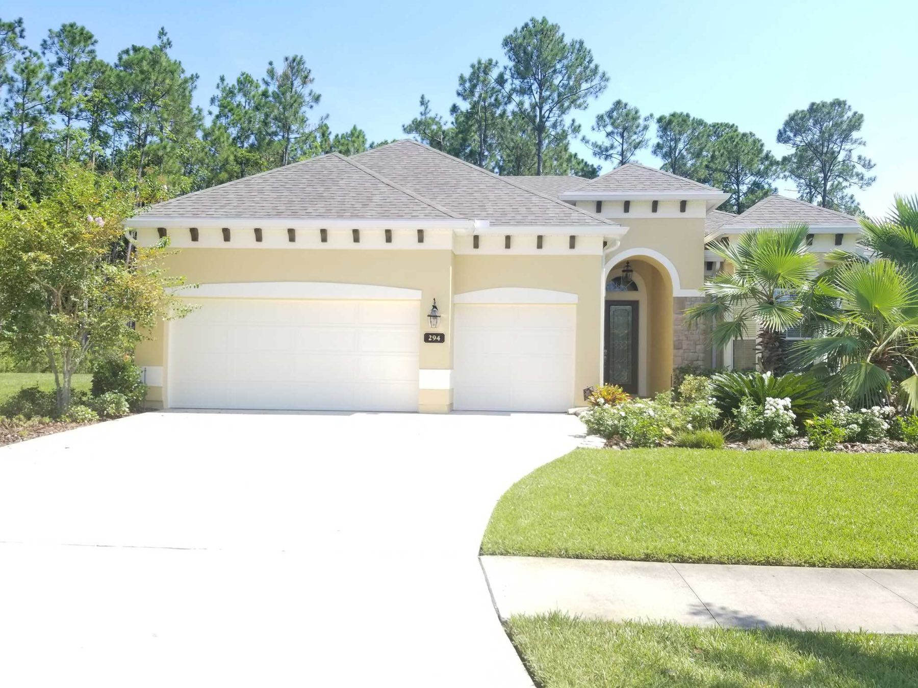 A repainted stucco home with a tile roof and palms in Ponte Vedra Beach, Florida