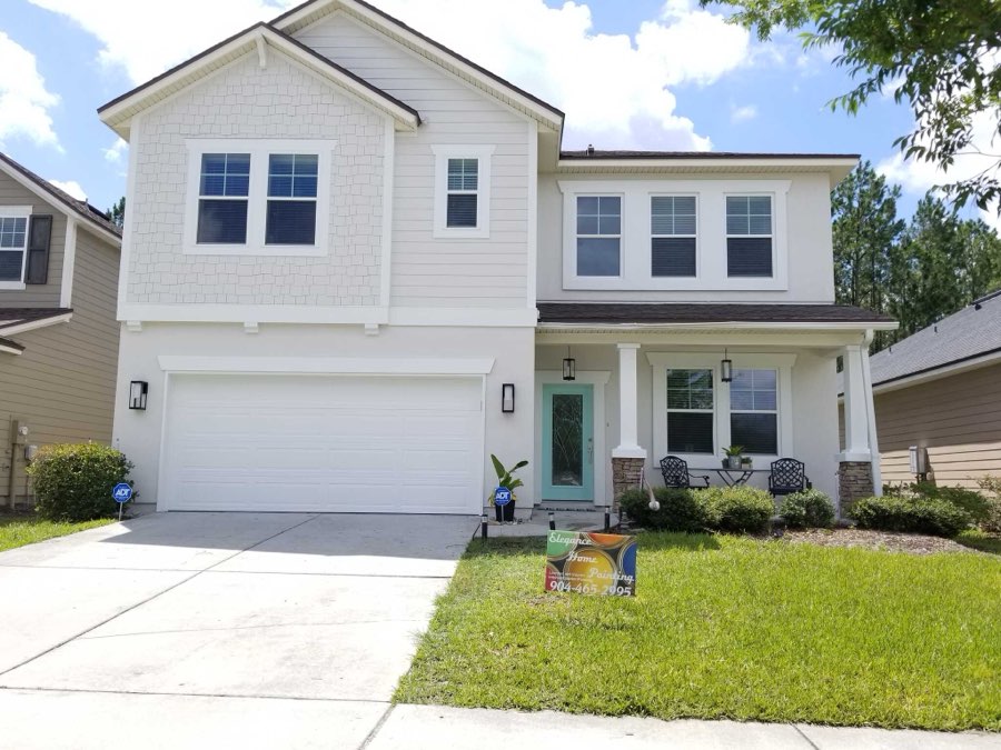 A two-storey home painted white with a teal front door and dark trim