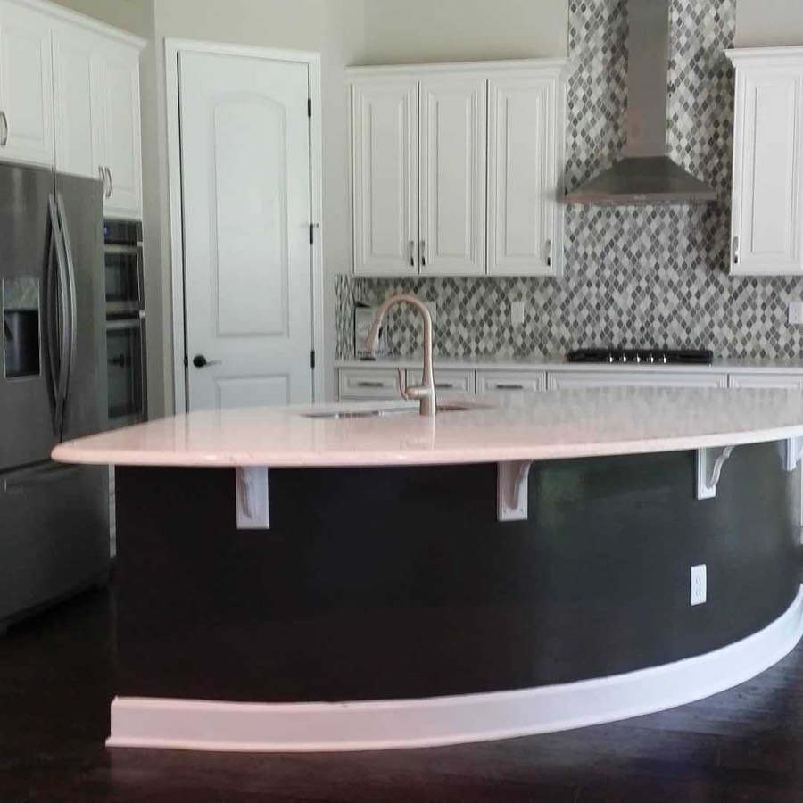 A kitchen with white cabinets and a curved island painted deep navy beneath a marble top