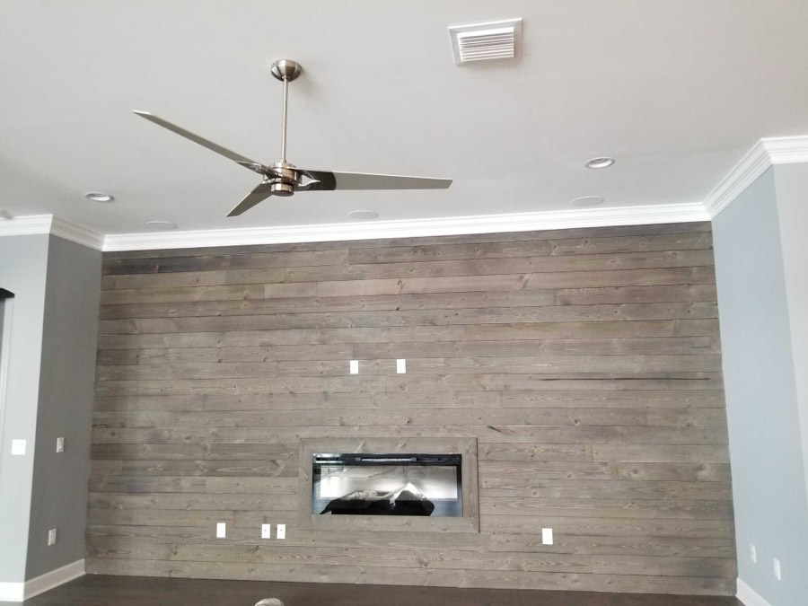 A living room feature wall clad in weathered horizontal planks around a linear fireplace